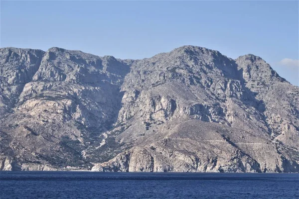 Rocky Coast Overhangs Water Its Gray Hills Stretch High Sky — Stock Photo, Image