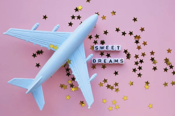 Sweet dreams words, gold stars and airplane on a pink background