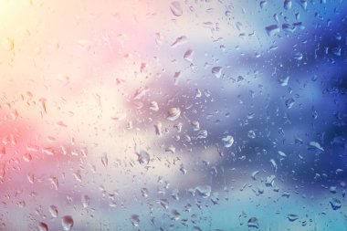 Yağmur su damlaları ile cam arka plan üzerinde güneş