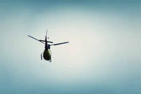 Mavi gökyüzünde uçan helikopter.