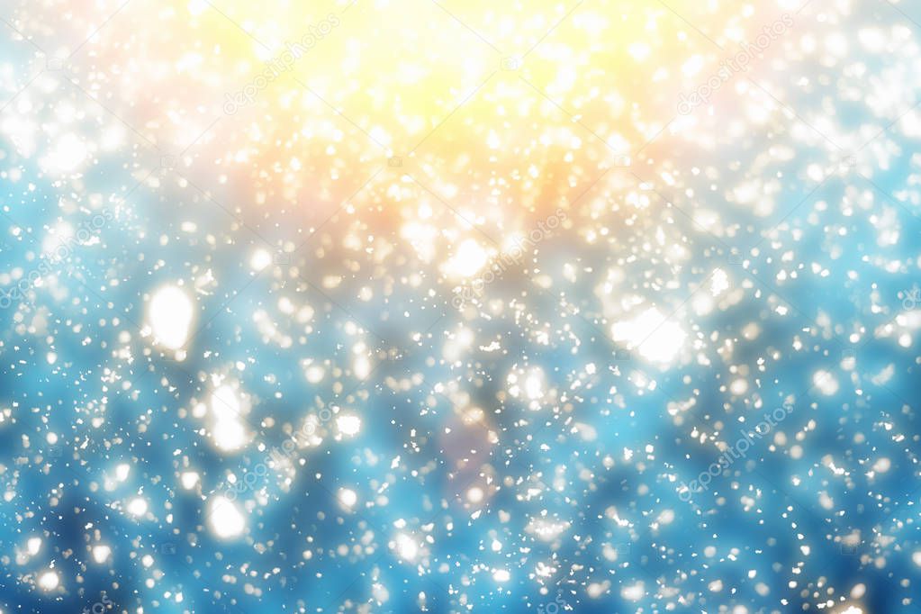 Christmas abstract golden bokeh glitter lights on blue background. Round defocused circle particles