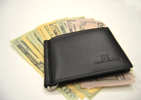 Wallet filled with money, on the white reflective tabletop. Wallet on a white background with a protruding money. Hryvnia. Cash is king. American Money. Money isolated on white. Room for text. American Money is used and collected world wide.