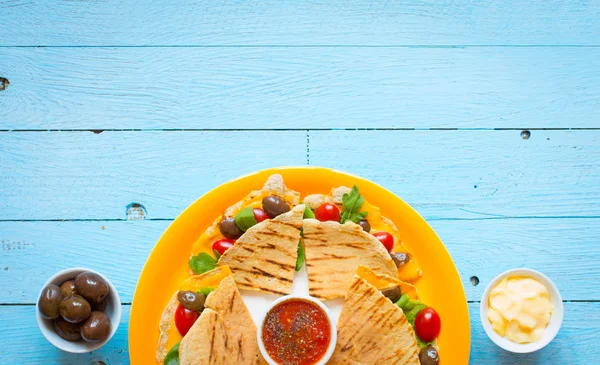 Pyszne wegetariańskie quesadillas z pomidorów, oliwek i sera cheddar w kolorowe danie nad drewnianym — Zdjęcie stockowe