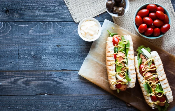 Hot dog with pickles, tomatoes and olives — Stockfoto