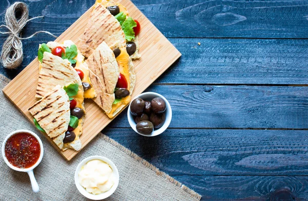 Delicious veggie quesadillas with tomatoes, olives, and cheddar cheese in a colorful dish over a wooden — Stock Photo, Image