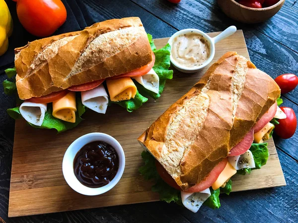 Вкусные и вкусные сэндвичи с индейкой, ветчиной, сыром, помидорами — стоковое фото