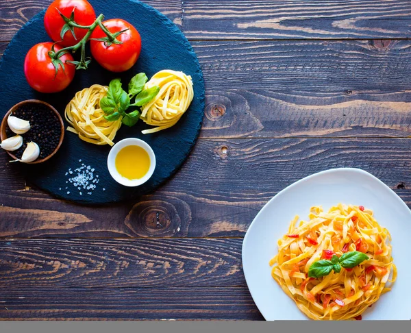 Tagliatelle mit Tomate und Basilikum, zu Hause zubereitet, auf einem hölzernen Bac — Stockfoto