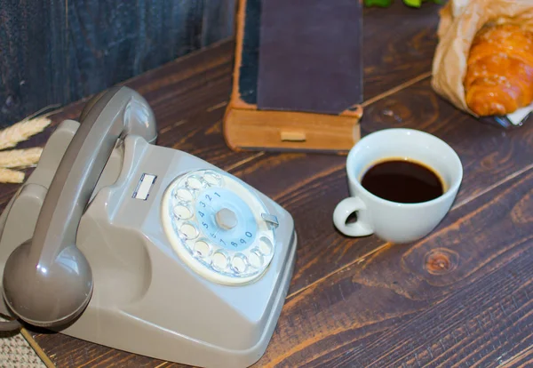 Старый старинный телефон, кофе, книга, на деревянном фоне , Лицензионные Стоковые Фото