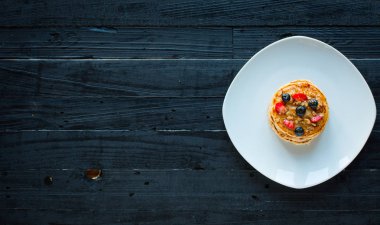 Taze çilek, çilek, yaban mersini ve koyu ahşap arka plan üzerinde akçaağaç şurubu ile ev yapımı gözleme. Metin için boş alan