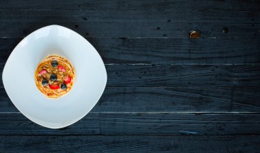 Taze çilek, çilek, yaban mersini ve koyu ahşap arka plan üzerinde akçaağaç şurubu ile ev yapımı gözleme. Metin için boş alan