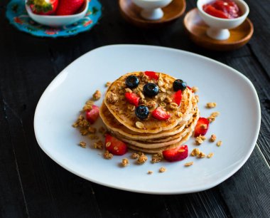 Taze çilek, çilek, yaban mersini ve koyu ahşap arka plan üzerinde akçaağaç şurubu ile ev yapımı gözleme. Metin için boş alan