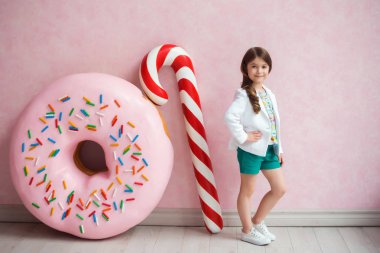 Noel candy ile pembe bir arka plan üzerinde koyu saçlı bir kız portresi