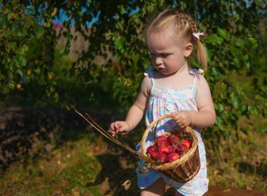 Kırmızı elma ile bir sepet ile'nın bahçesinde oynayan sarışın kız