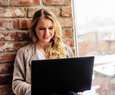 Penceredeki bir tuğla duvara dizüstü bilgisayar ile kız