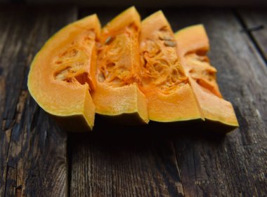 Tahta bir masada dilimlenmiş olgun portakal kabağı.