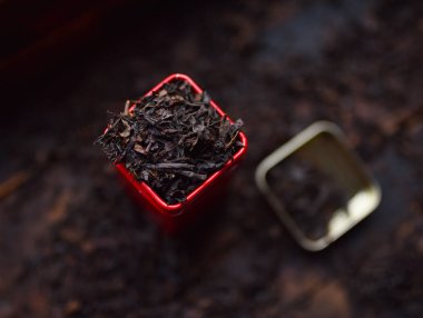 Siyah çay kırmızı bir teneke kutuda koyu bir arka planda