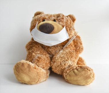 Tıbbi maske takan peluş oyuncak ayı.