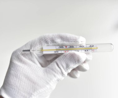 beyaz bir eldiven ve cıva bir termometre.