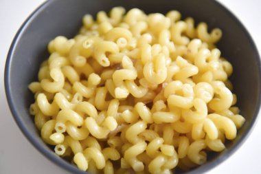 Beyaz arka planda bir tabakta etli haşlanmış makarna.