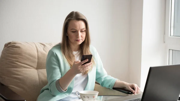 Bir kız telefonda dizüstü bilgisayarın yanında konuşuyor.