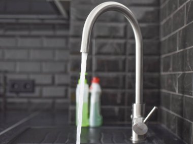 Çelik bir musluktan su akar.