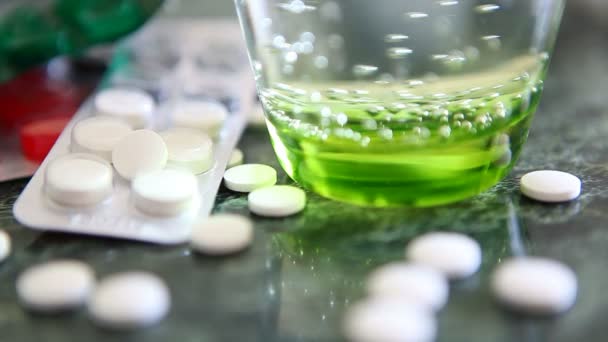 Medicamentos y vaso de agua sobre mesa verde. Enfermedad, concepto de gripe — Vídeo de stock