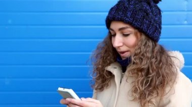 Sms kopya alanı ile mavi duvarının yakınında yazma kıvırcık saçlı kız