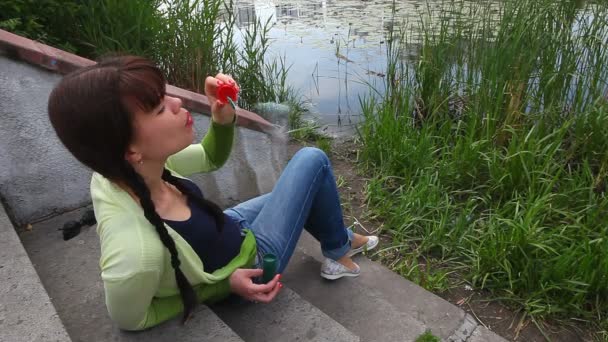 Красива дівчина робить бульбашковий вентилятор в міському парку, біля озера і очерету — стокове відео