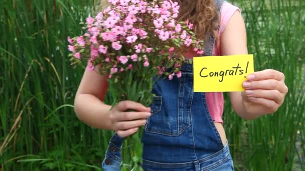 Congrats - mooie vrouw met kaart en roze bloemen — Stockvideo