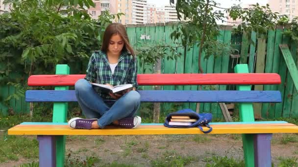 Hermosa adolescente leyendo libro al aire libre — Vídeos de Stock