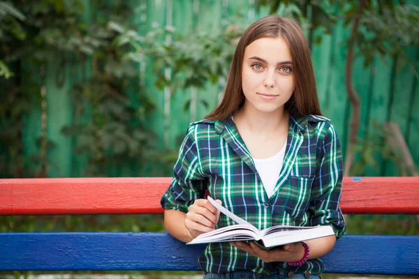 Красива студентка читає книгу на відкритому повітрі — стокове фото
