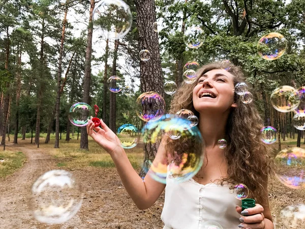 Mutlu genç kadın parkta kabarcıklar üfleme