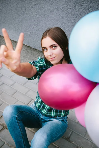 Hermosa joven con globos muestran señal de victoria por los dedos — Foto de Stock
