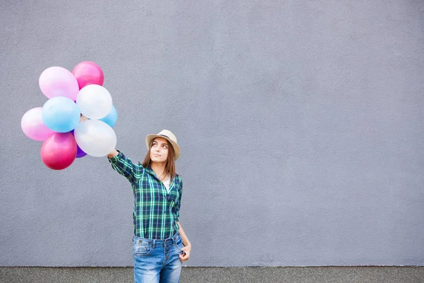 Ragazza felice con palloncini vicino al muro grigio con spazio copia — Foto Stock