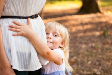 Küçük kız annesi ve gülümseme açık havada sarılma
