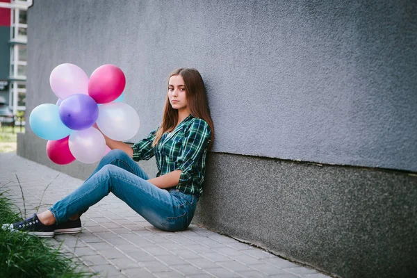 Açık havada renkli hava balonları ile oturan güzel hüzünlü kız