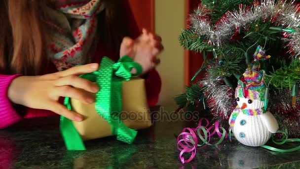 Jovem desempacota uma caixa de presente perto da árvore de Natal — Vídeo de Stock