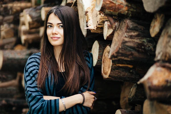 Красива молода жінка з дровами на фоні — стокове фото