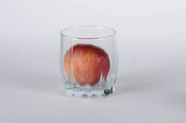 Roter Apfel im Glas auf weißem Hintergrund — Stockfoto