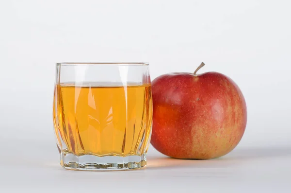 Красное яблоко позади стакана с яблочным соком на белой backgroud — стоковое фото