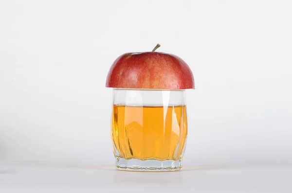 Half red apple in a glass of juice — Stock Photo, Image
