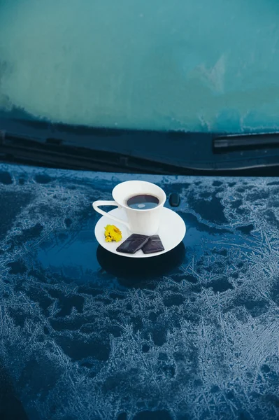 Cup of coffee on a frozen blue car — Stock Photo, Image