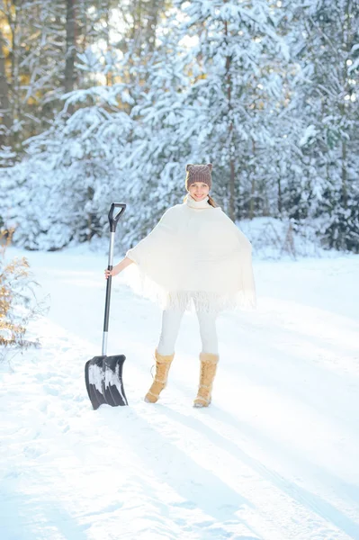 女人为背景，用铲子把冬季森林将雪上霜和阳光明媚的一天中删除 — 图库照片