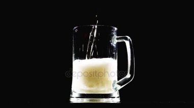 Bira siyah arka plan üzerine bir cam içine yağıyor. Ağır çekim