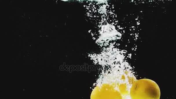 Lots of oranges falling into water in slow motion — Stock Video