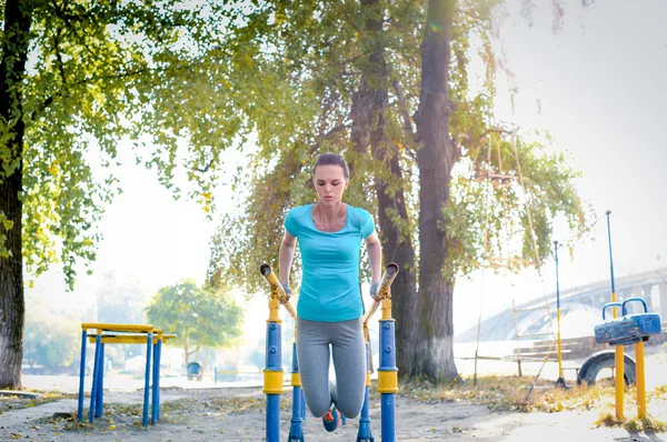 Mujer haciendo ejercicio en barras paralelas — Foto de Stock