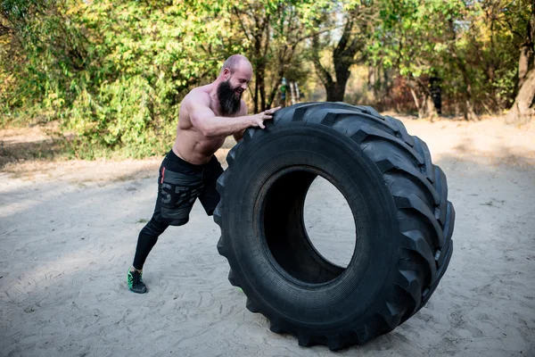 Muscular man working out with heavy tire — Stock Photo, Image