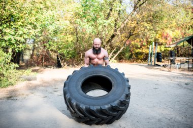 Man lifting a large tractor tire clipart