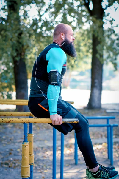 М'язистий бородатий чоловік на паралельних брусах — стокове фото