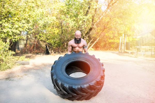 Sportsman exercising with tire — Stock Photo, Image